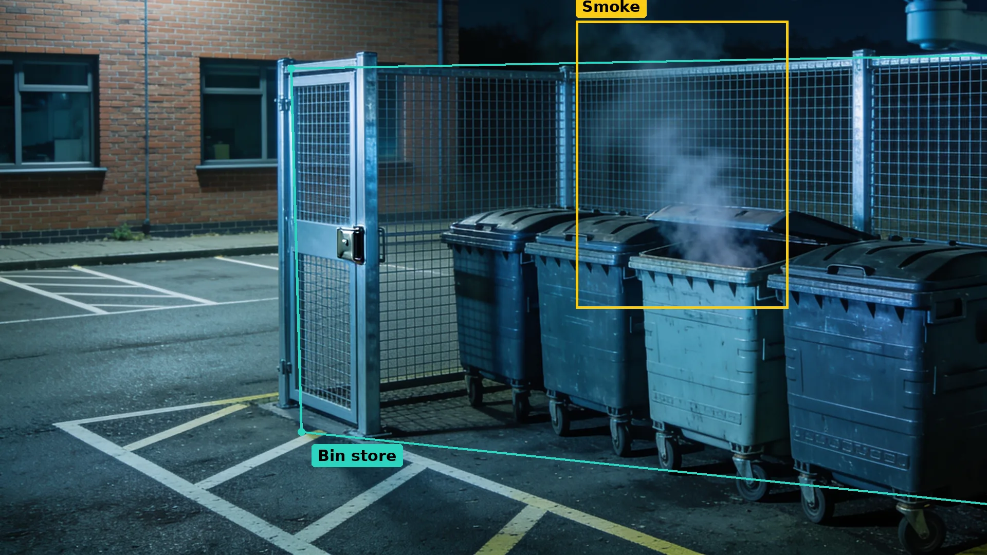 Night CCTV of a locked mesh bin compound in a teal zone, smoke from one wheelie bin boxed in amber