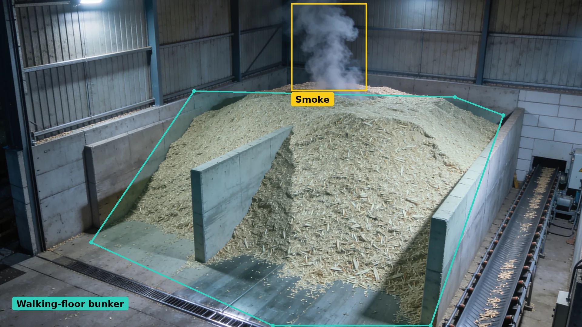 Night CCTV of a wood chip bunker with push walls in a teal zone, smoke at the back boxed in amber, conveyor at right