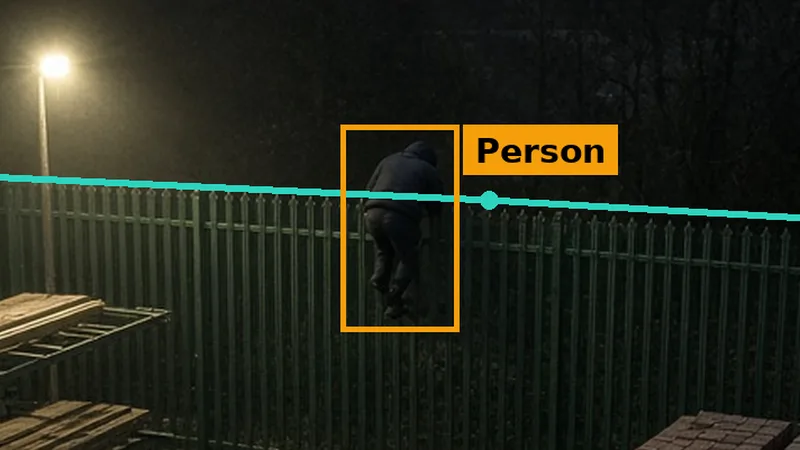 Phone alert crop: a figure on a builders merchant yard fence at night, crossing a teal fence line