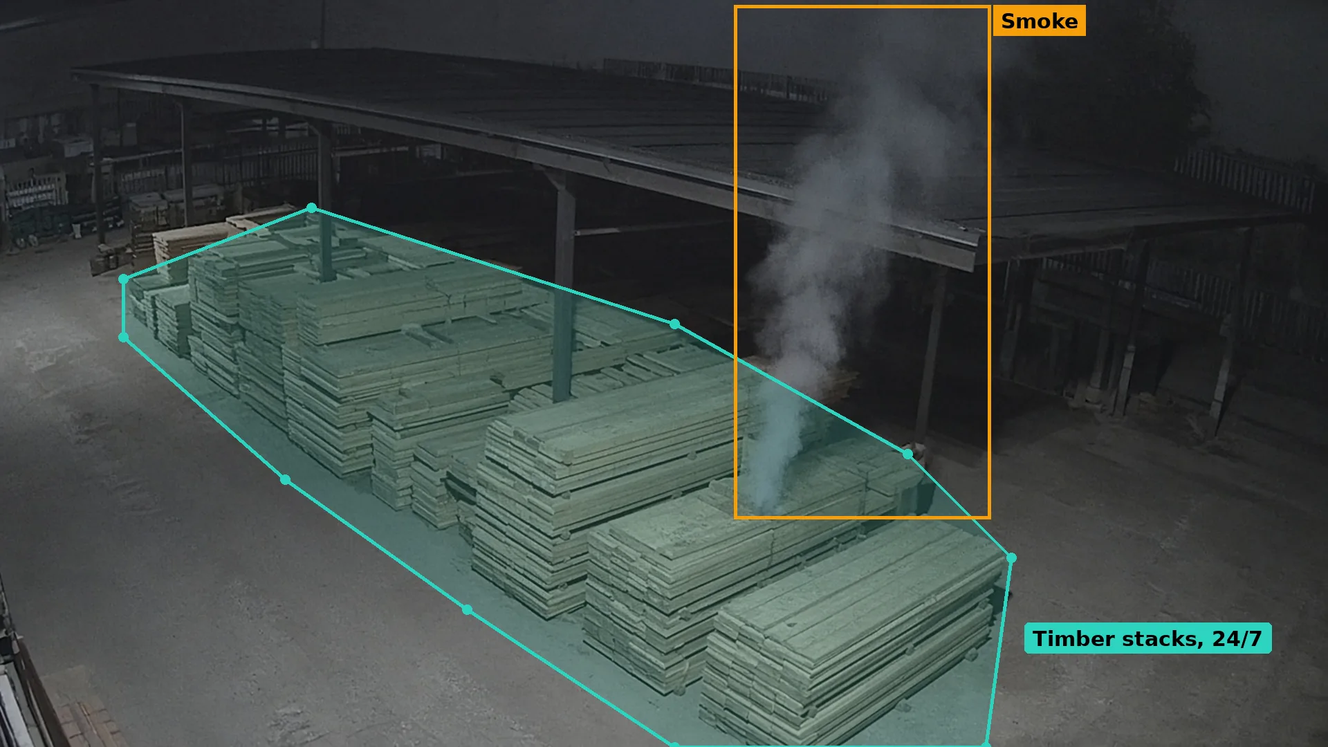 Night CCTV of thin grey smoke rising from a stack of sawn timber in an open-sided timber store, boxed in amber