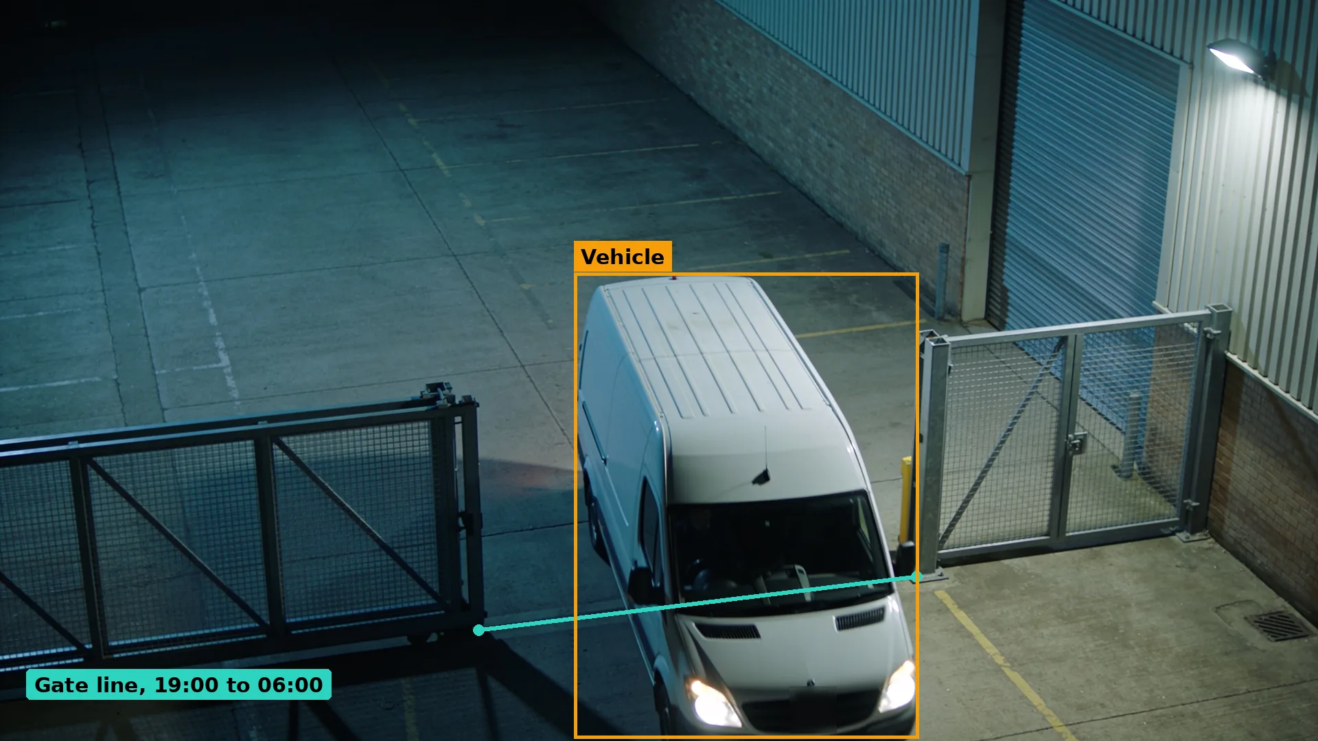 Night CCTV of a white van driving through open steel mesh gates into an empty business yard, boxed in amber