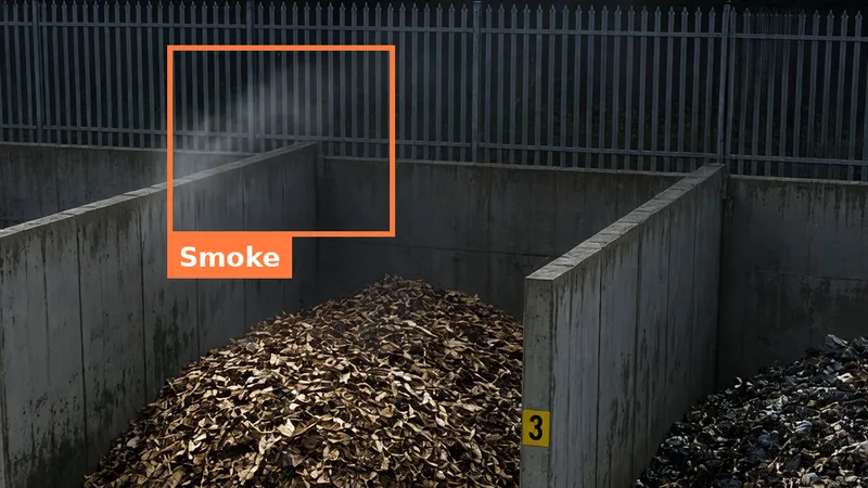 CCTV still of smoke rising above a wood chip bay at night, boxed in orange, as shown in an alert