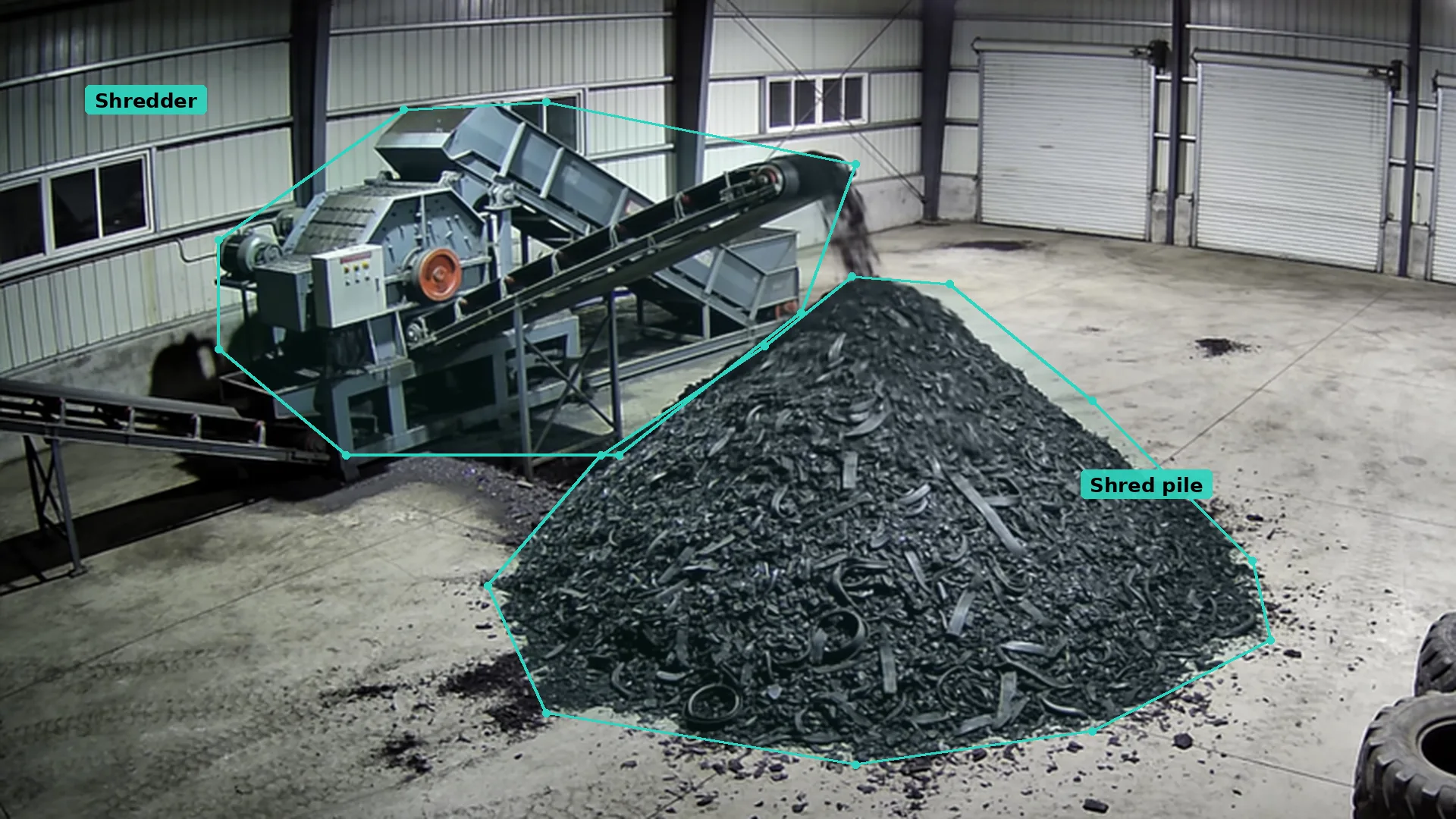 Night CCTV inside a tyre shredding building: a teal zone round the shredder and another round the pile of rubber shred