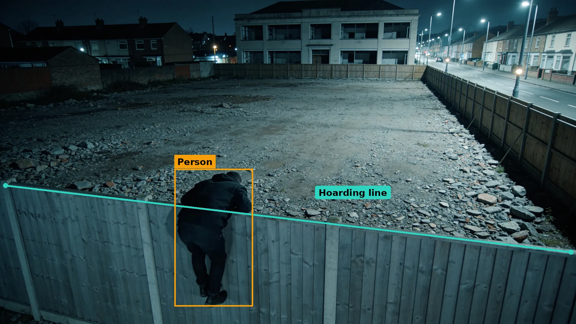 Night CCTV of a cleared site behind timber hoarding, a person climbing over boxed in amber, hoarding top in teal