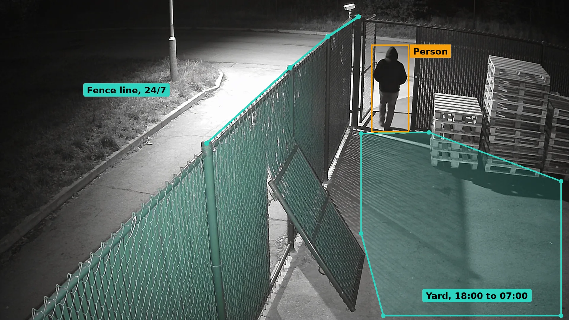 Black and white night CCTV of a person walking through a yard gate beside a pushed-in mesh fence panel, boxed in amber