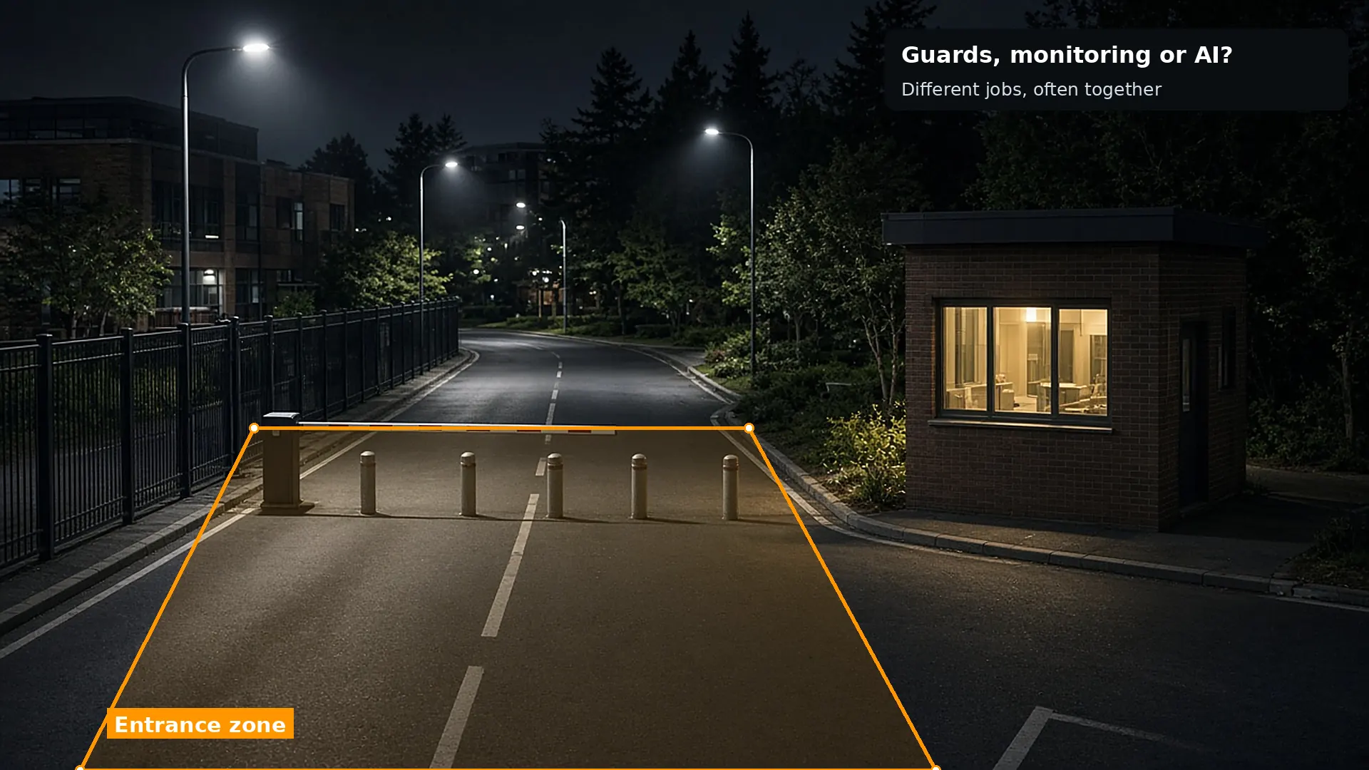 Night view of a business park entrance with a lit lodge, bollards and a lowered barrier