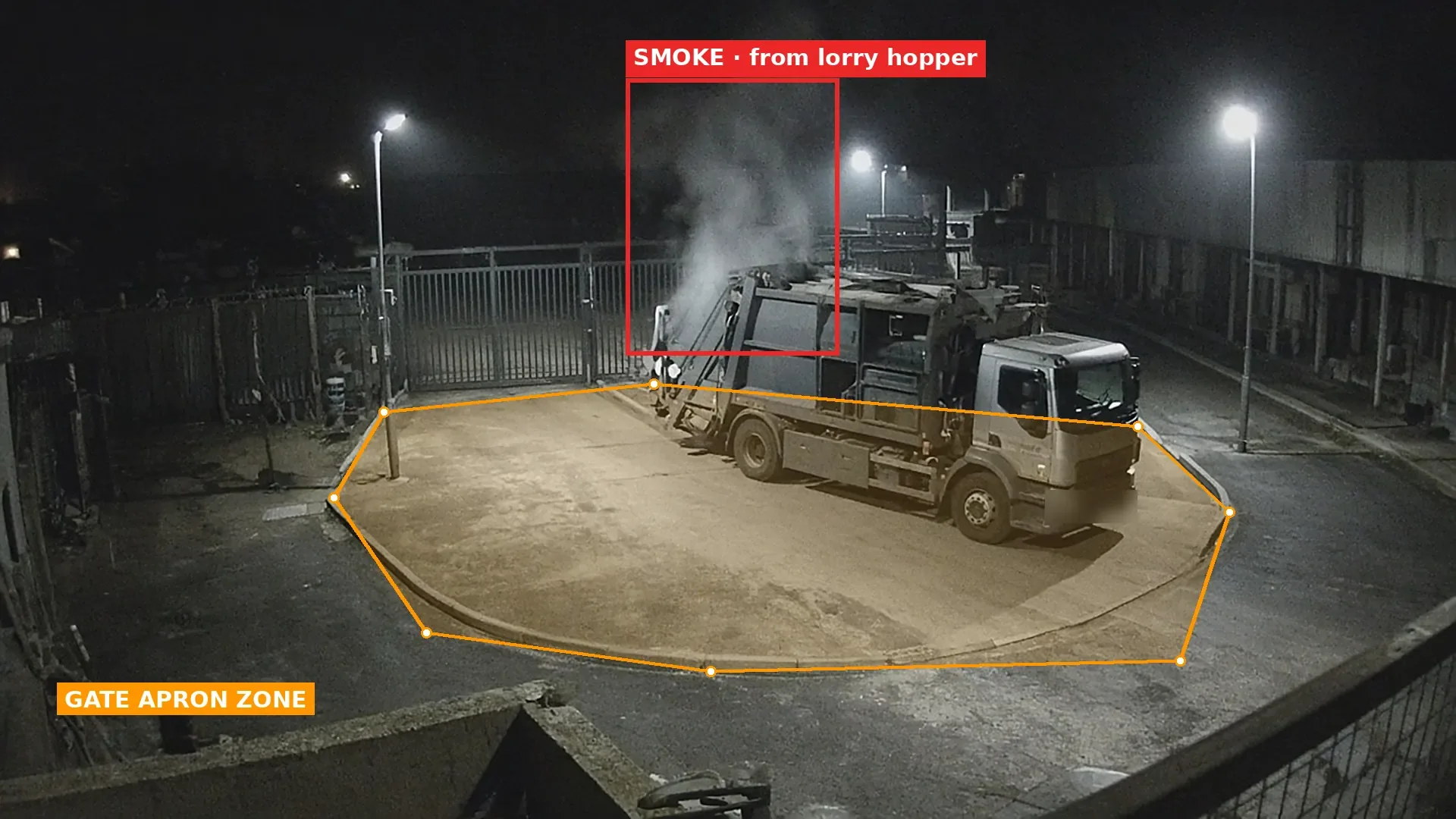 Night CCTV view of a refuse collection lorry parked on a lit gate apron, with grey smoke rising from its rear hopper boxed in red and an orange polygon zone drawn around the apron